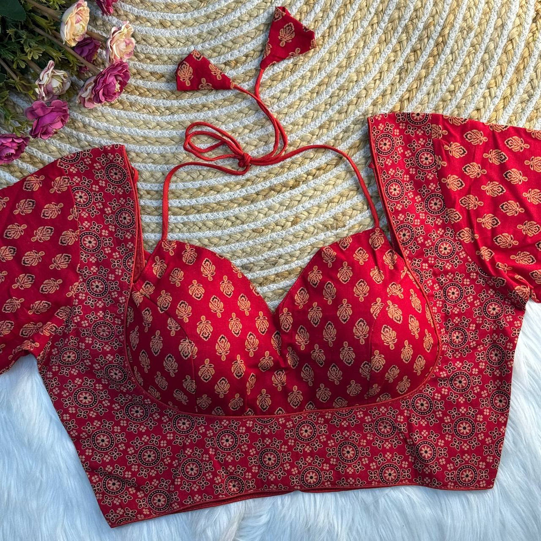 Red patterned bikini Blouse on a textured surface with flowers.