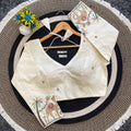White embroidered blouse on a round mat with a hanger and decorative items.
