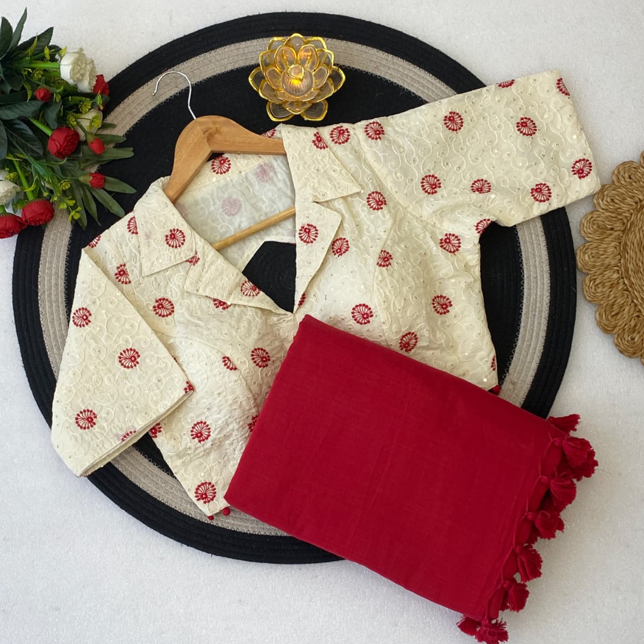 Traditional outfit with a cream blouse and red saree on a decorative plate