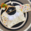 Embroidered blouse with floral collar and sleeves on a hanger against a textured surface.